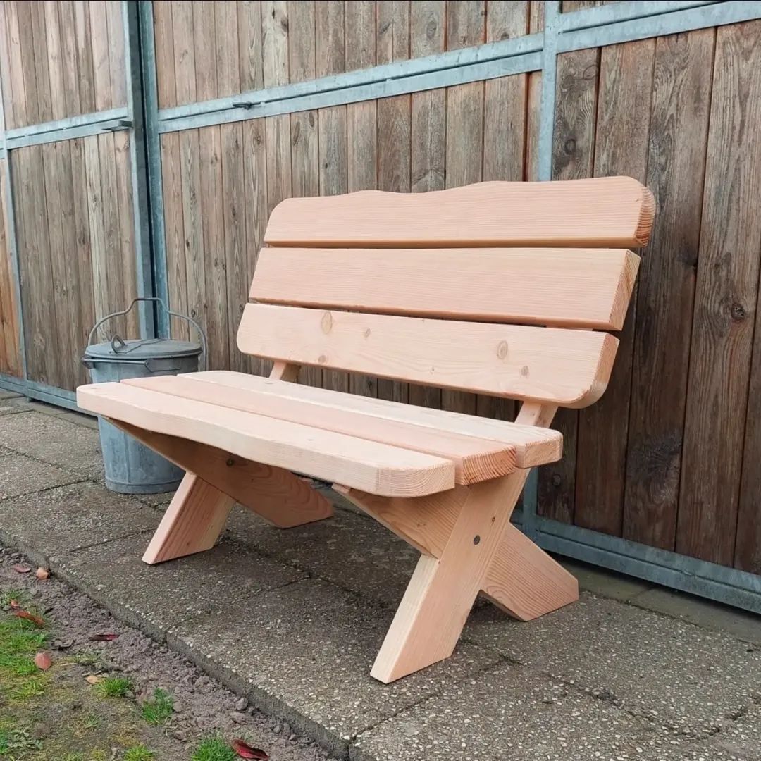 Tuinbankje op maat in licht hout tegen een houten schutting