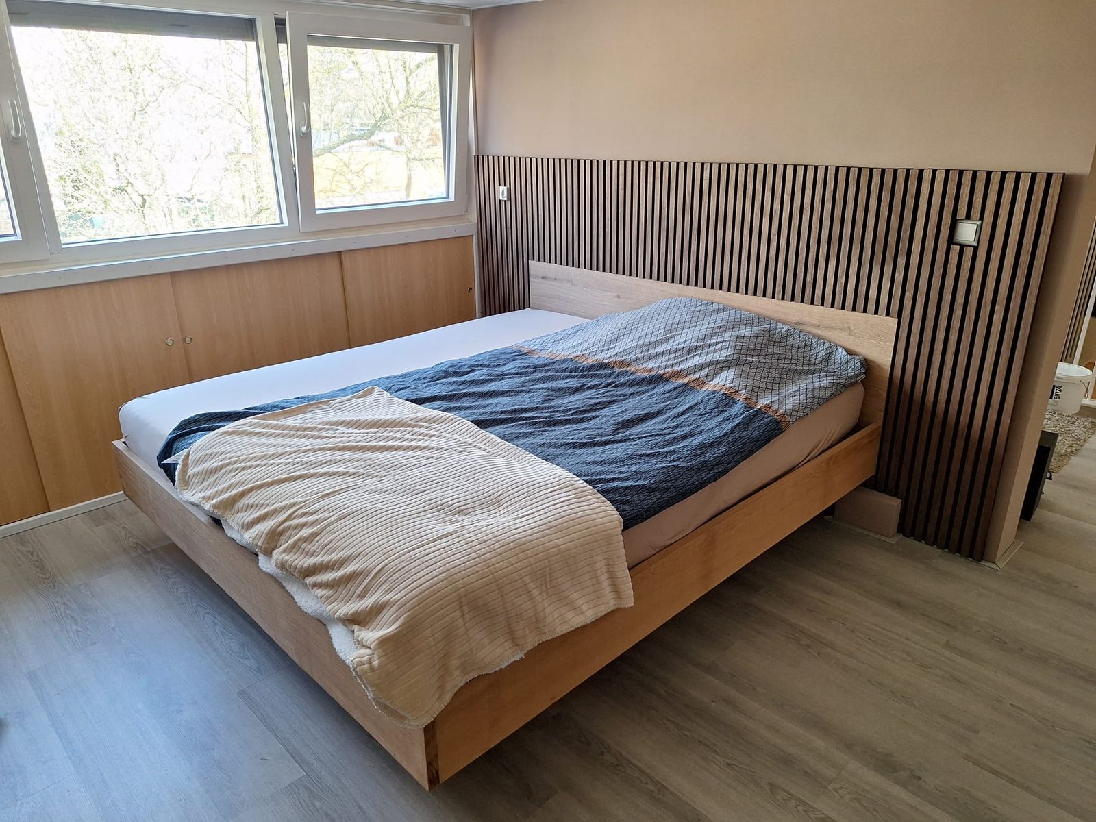 Bed op maat in licht hout met een verticale lattenwand als hoofdeinde