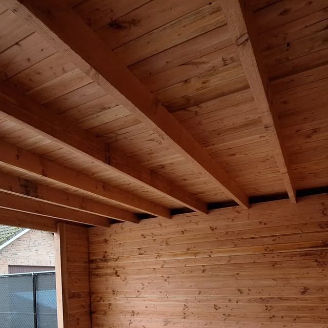 Onderkant van een houten overkapping met balken en een schroten plafond